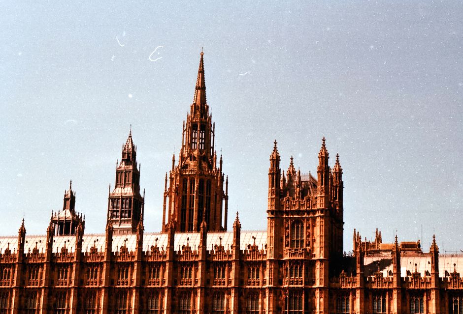 Towering Gothic Revival architecture of the Palace of Westminster under a blue sky in London.