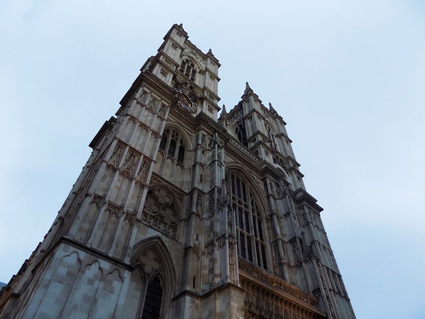 Low-angle view of Westminster Abbey's Gothic architecture with a clear sky backdrop.